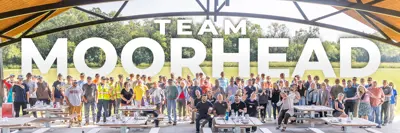 Photo of staff at an employee picnic with the text Team Moorhead behind it